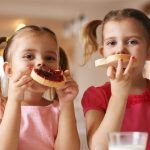 Girls eat breakfast on the table in the living room. Looking at camera. (credit: Thinkstock)
